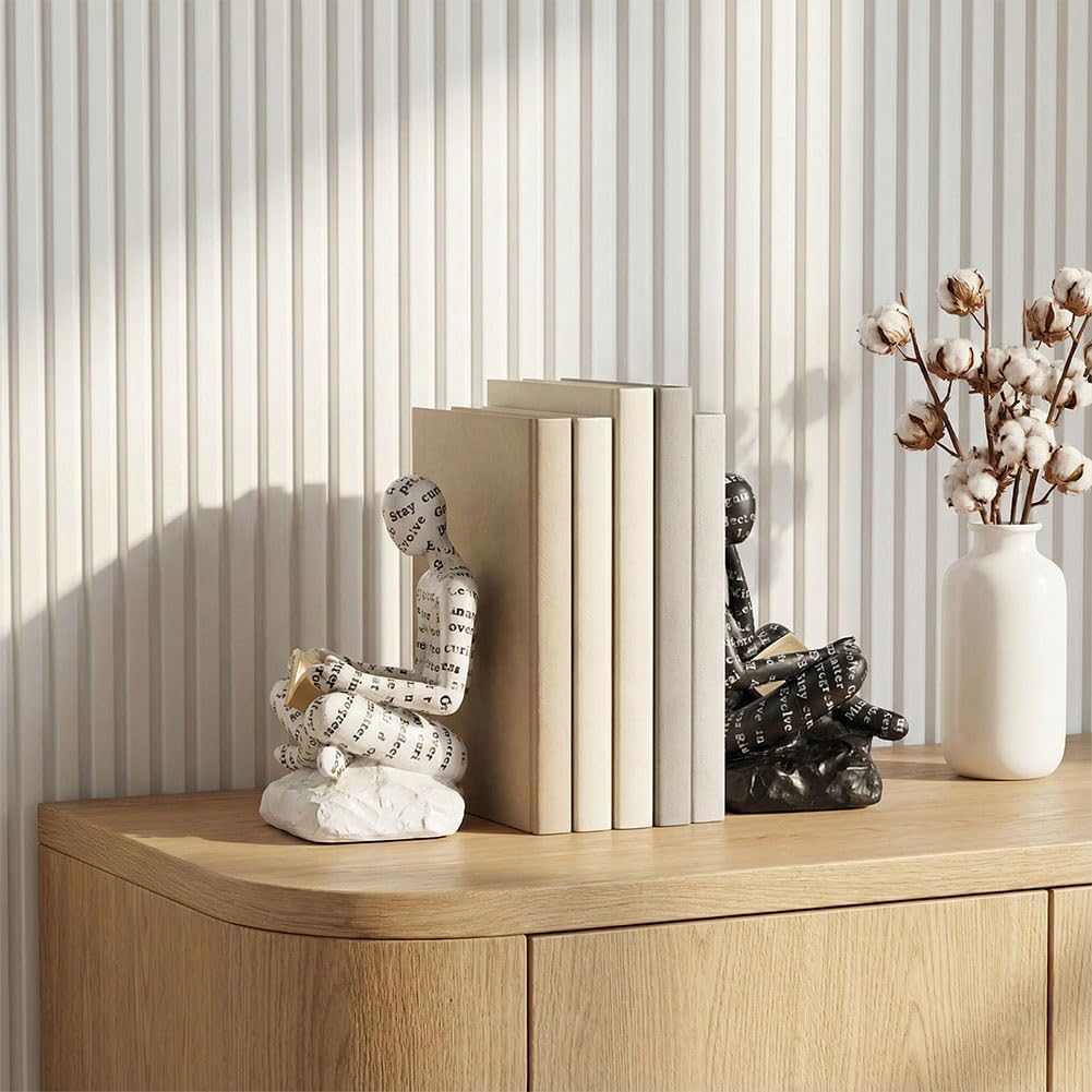 Thinker bookends styled on a light oak bookshelf with a dried palm leaf and stacked books