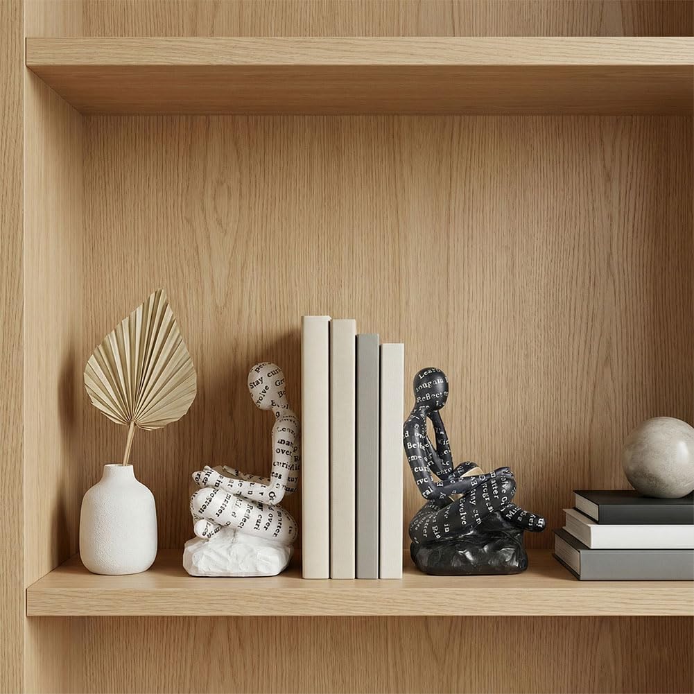 Thinker bookends holding books on a round travertine coffee table beside a white mug